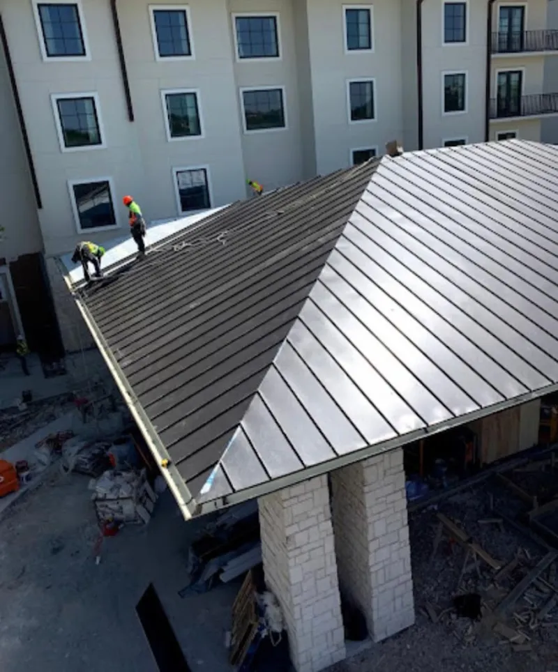 Crew installing standing seam metal roof panels on a commercial project in Hurst